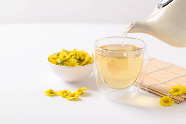Organic Chrysanthemum flower tea in a cup and teapot on white background, Healthy Herbal drink