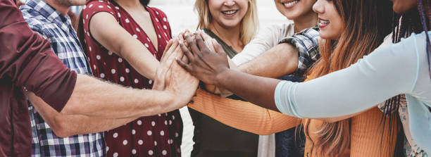 istock Young happy people stacking hands outdoor - Multiracial students celebrating together - Focus on black hand 1288253338