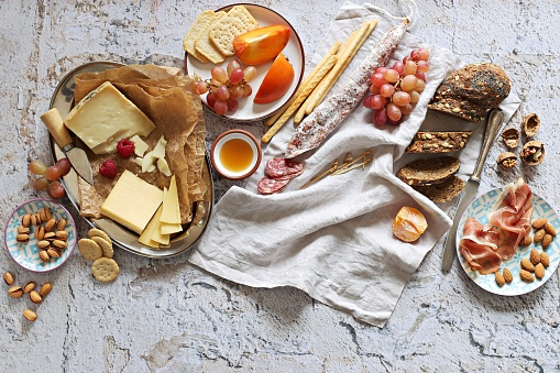 Appetizers table with various of cheese, curred meat, sausage, olives, nuts and fruits. Festive family or party snack concept. Overhead view.