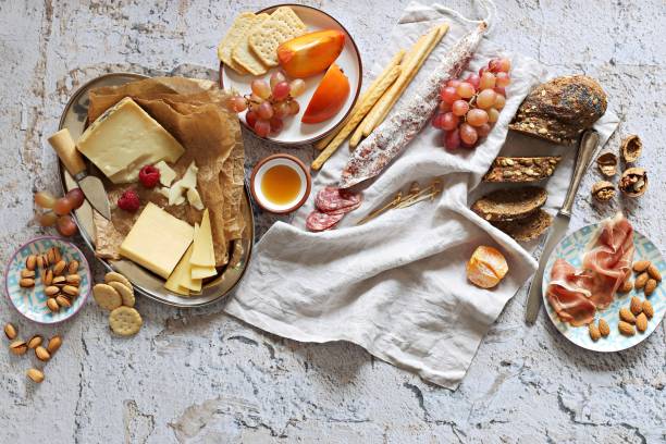 закуски стол с различными сыр, понесенные мясо, колбаса, оливки, орехи и фрукты. - wine cheese food salami стоковые фото и изображения