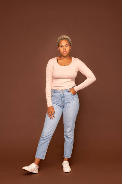 istock Young serious mixed-race female in blue jeans and white pullover in isolation 1288254857