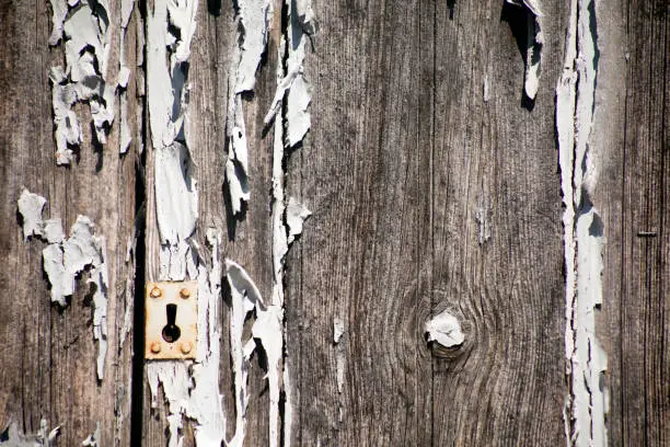 Old wooden closed door , keyhole, paint peeling off, copy space on the right side of the image. Galicia, Spain.