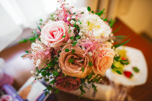 bouquet of beautiful flowers with roses in a small vase in vintage style on the table