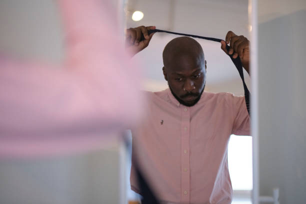 아프리카계 미국인 남자 에 셔츠 드레싱 과 조정 넥타이 에 목 에 집에서 - necktie pink shirt luxury 뉴스 사진 이미지
