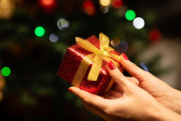 istock Woman's hand holding a Christmas present 1288257395
