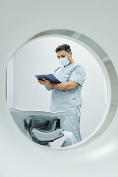 istock Mature doctor in uniform and protective mask making notes in medical document 1288262424