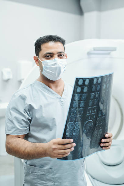 istock Professional mixed-race radiologist in mask and uniform holding x-ray image 1288262443