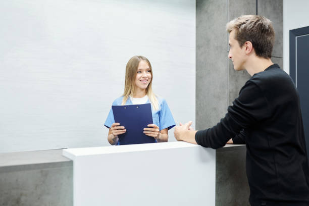 istock Happy young female assistant or receptionist in blue uniform holding clipboard 1288262489