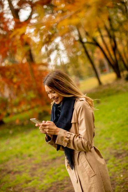 istock Young woman using mobile phone in the autumn park 1288263707