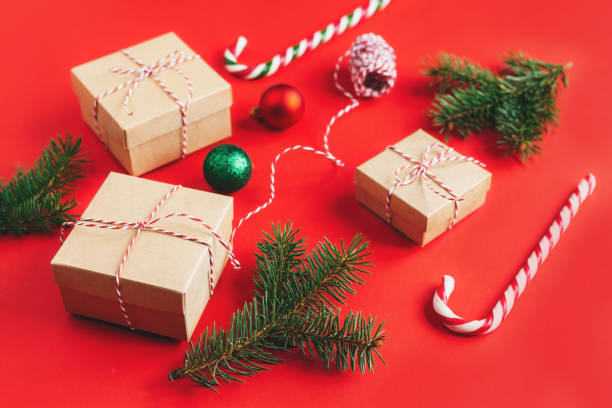 istock Craft gift boxes with spruce branches, balls and candy canes on a red background. 1288269062