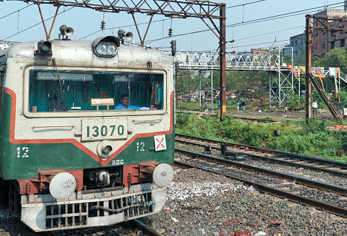 West Bengal, 11-22-2020: A train (locomotive) driver seen in his (driver's) cabin driving an Indian Railway passenger train, passing through littered railroad track, near Liluah, Howrah.