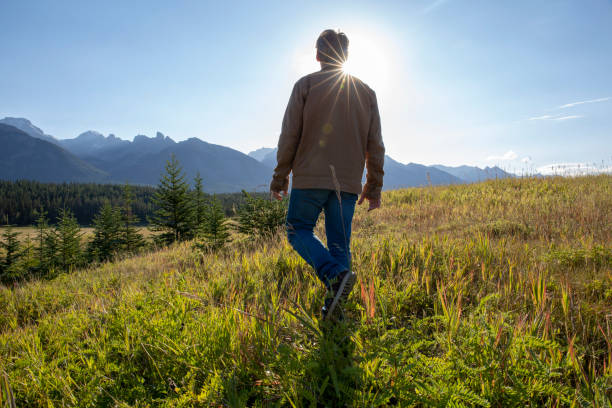 istock Man walks through grassy meadow in the morning 1288271566