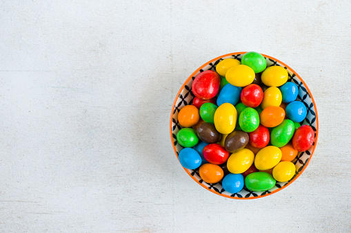 M&M's candy in the bowl on the white background, colorful candy texture, multicolored gradient.