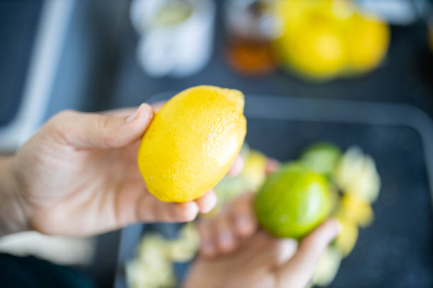istock Female hands holding a lemon and a lime above fruit slices 1288275495