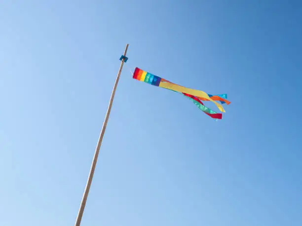 Rainbow colored wind sock fluttering in the wind on a clear blue sky day