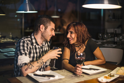 Young modern couple in restaurant drinking wine with ambient light, happy time at dinner in the night.