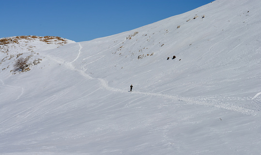 One teenage latino boy skiing down a snow covered run.