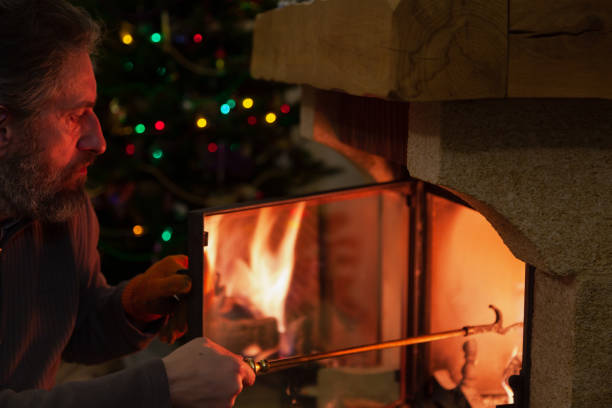 istock Man sits in front of burning fireplace. Behind Christmas tree 1288278495