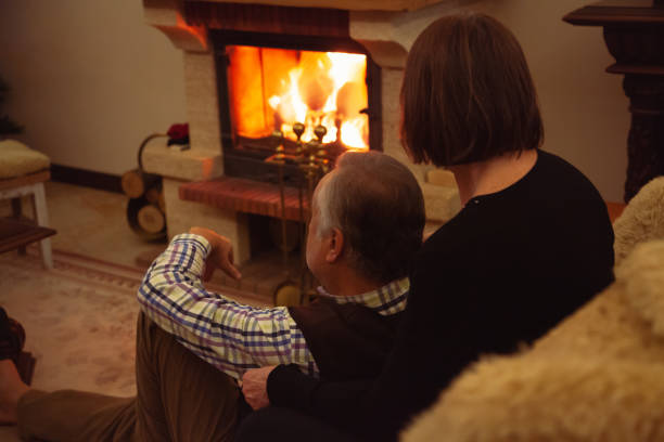 istock Elderly married couple sitting in front of  fireplace 1288278544