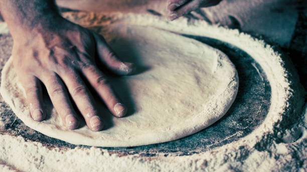 hands of pizza chef prepares pizza on workbench - pizzeria imagens e fotografias de stock