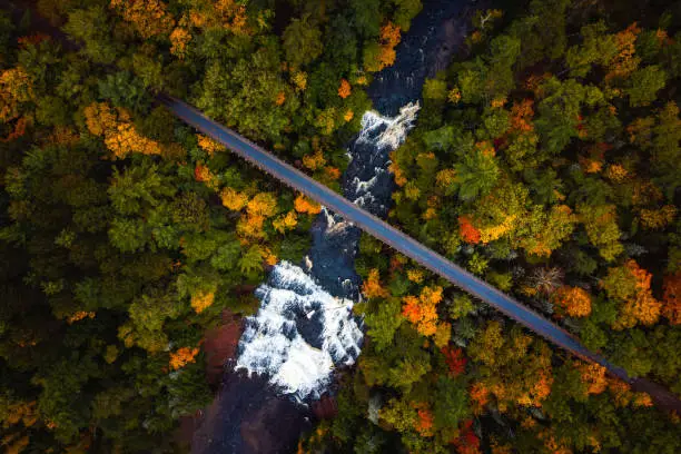 Photo of Beautiful look down travel aerial photograph of the abandoned railroad bridge crossing the Ontonagon River and scenic Agate Falls waterfall below surrounded by forest of evergreen and deciduous trees.