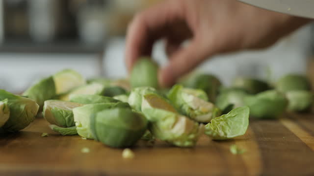 hand cut brussels sprouts into half on wooden cutting board