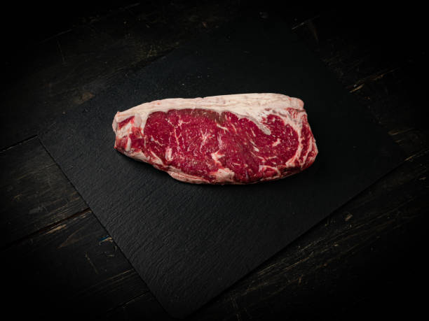 Raw ribeye beef steak on a black plate. Raw ribeye beef steak on a black plate. Top view. report card stock pictures, royalty-free photos & images