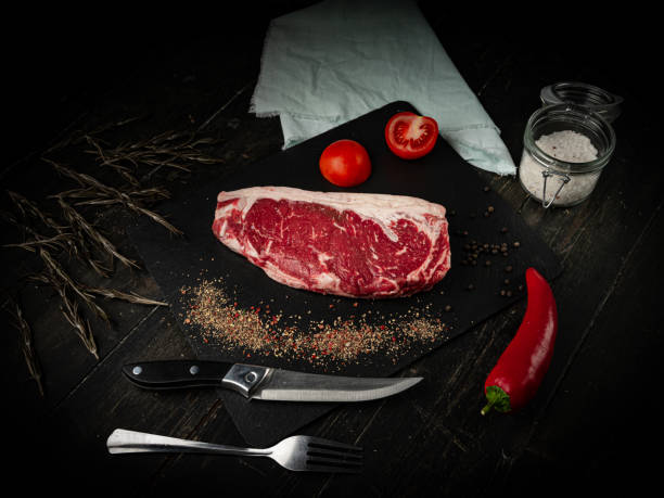 istock Raw ribeye beef steak on a black plate. 1288287342