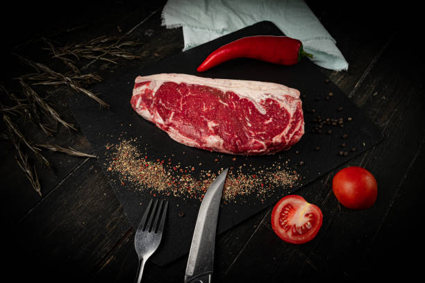 istock Raw ribeye beef steak on a black plate. 1288288359