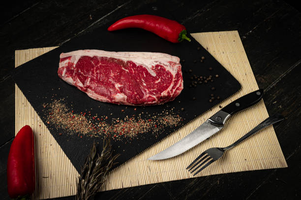istock Raw ribeye beef steak on a black plate. 1288290373