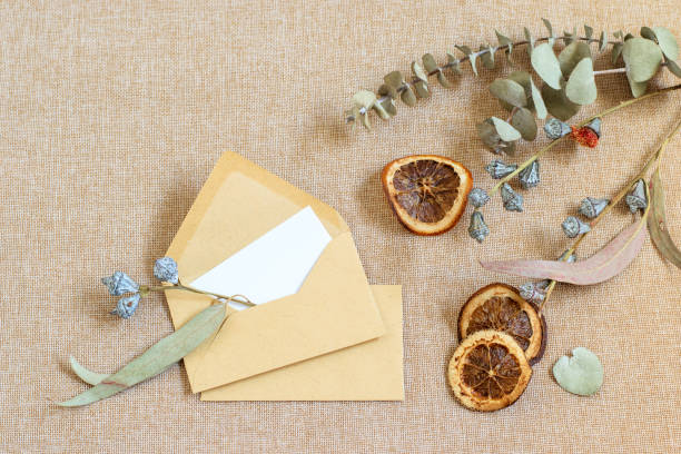 istock Empty envelopes on the burlap textured background. Dry tangerines and eucalyptus leaves. Zero waste mock up photo with copy space. 1288291040