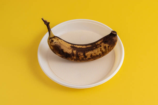 zgniły banan w plastikowej płycie na żółtym tle. - banana rotting ripe above zdjęcia i obrazy z banku zdjęć