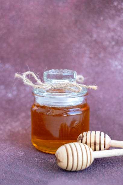 Glass can full of honey and wooden stick stock photo
