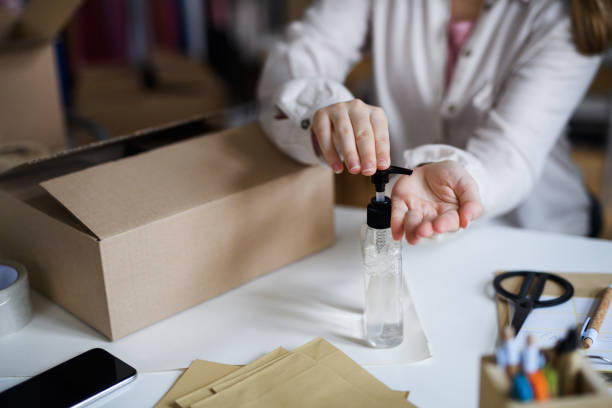 istock Unrecognizable woman dropshipper working at home, disinfecting hands. Coronavirus concept. 1288294989