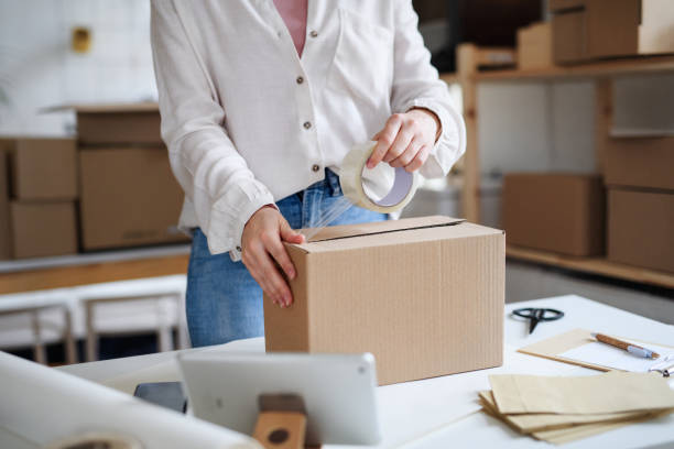 istock Unrecognizable woman dropshipper working at home, packing parcels. Coronavirus concept. 1288295030