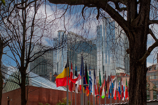 Row of flags of member states of the European Union in front of the European Parliament in Brussels. As seen from the Brussels Leopold Park with view on the European Parliament. The Parliament's committee meetings are held primarily here in Brussels. The Paul-Henri Spaak building of the European Parliament was named after former President Paul-Henri Spaak. It houses the plenary sessions as well as a press centre and offices for the Parliament's president. It has a striking cylinder-shaped glass dome.