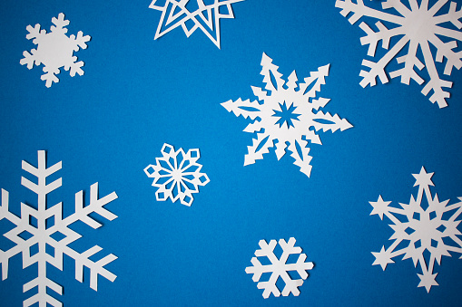 Paper cut white snowflakes on blue background