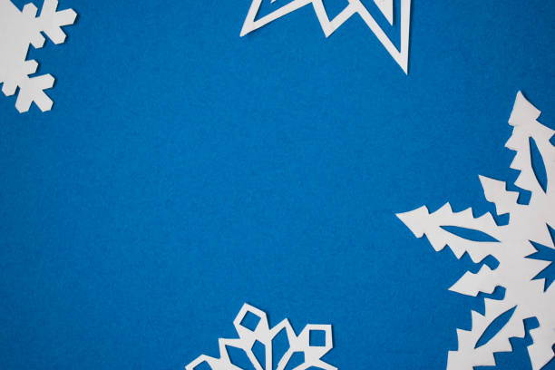 istock Cut out paper snowflakes on blue background 1288296287