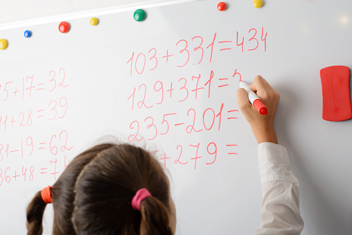 Female learner counting big numbers on the whiteboard