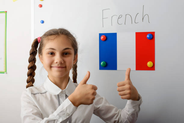 jeune élève gai de l’école secondaire dans l’uniforme blanc avec des queues de cochon restant devant le tableau blanc et affichant des pouces vers le haut. - langue française photos et images de collection