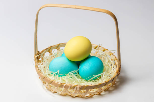 istock Colored eggs in a basket isolated on white background. 1288298784