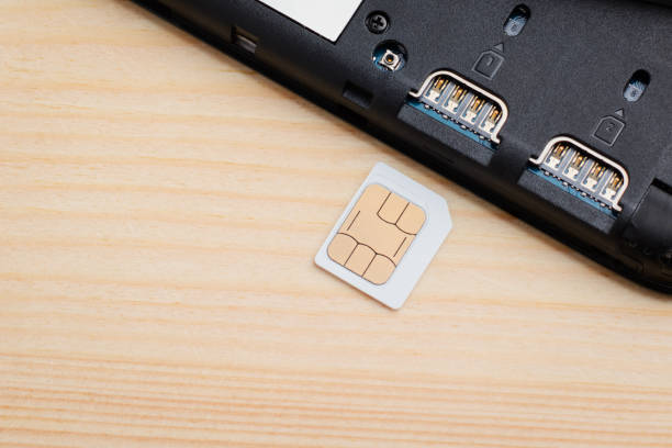 istock Micro SIM card near SIM port of a mobile phone on table 1288299584