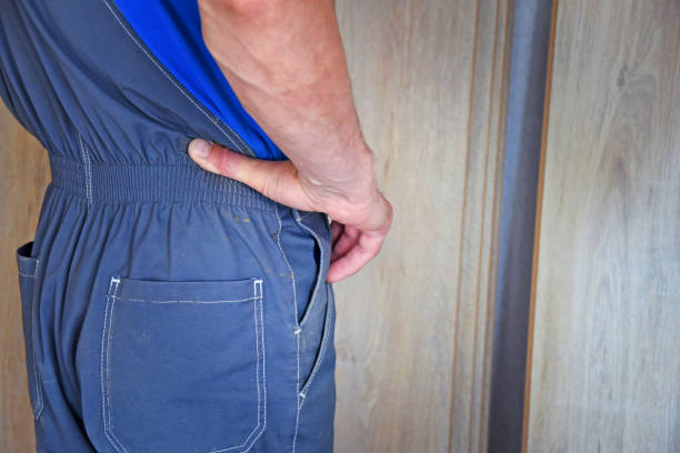 istock Working carpenter in overalls keeps his hands on his belt 1288300627
