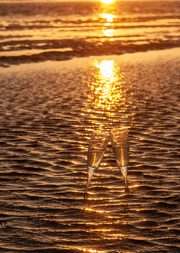 Two glasses of champagne on the sand of Tarifa beach at sunset