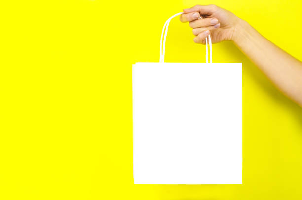 istock White paper bag in a female hand on a yellow background 1288306080