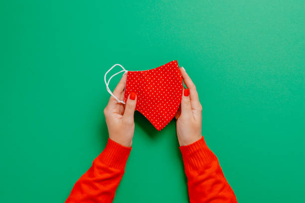 istock Woman holding a face mask on the green backdrop 1288306543