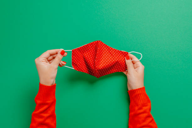 istock Woman holding a face mask on the green backdrop 1288307142