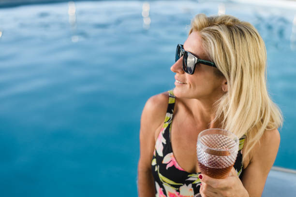 istock Woman holding drink by the poolside 1288307166