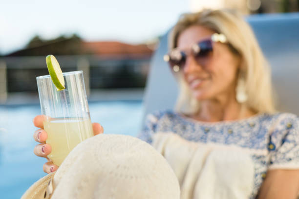 istock Woman drinking caipirinha on pool chair 1288307224