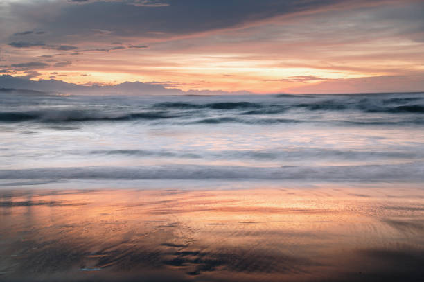 A long exposure photo of a beach under a beautiful sunset sky